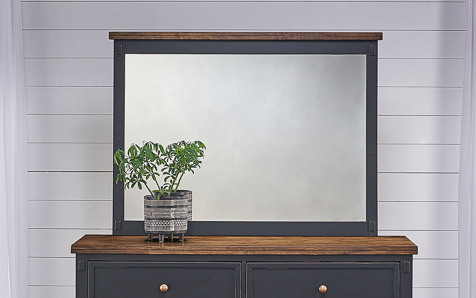 A-America mirror with solid hardwood frame, featuring a two-tone Chicory and Slate Black finish. Distressed black and brown design with chicory-finished wood knobs. Dimensions: 38.5" height, 52" width, and 2.25" depth.