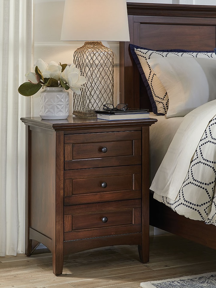 A-America 3-drawer nightstand made from solid mahogany wood in a cherry brown finish. Features medium wood tone with distressing and dark antique bronze hardware, adding a classic touch to any bedroom.